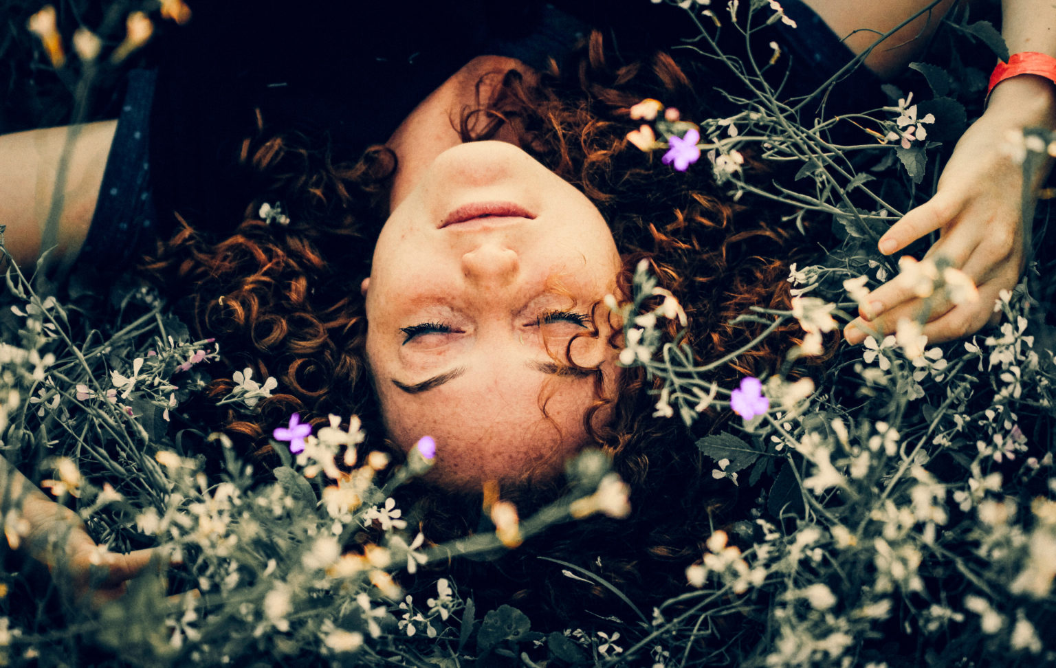 Photo d'une femme couchée dans l'herbe avec des fleurs.